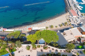 An aerial view of a coastal area with a beach, boats, and a parking lot. - Hotel Terme Cristallo Palace  (Casamicciola Terme)