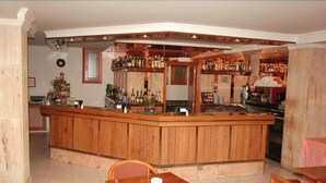 Un espace bar avec des meubles de rangement en bois, un comptoir et un coin salon comprenant une table et des chaises.