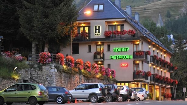 Un hôtel reconnaissable à son grand panneau en forme de «H», à ses balcons ornés de fleurs rouges et à son mur en pierre.