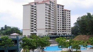 A multi-story hotel with a swimming pool and surrounding greenery. - Lumut Valley Resort Condominium (Lumut)