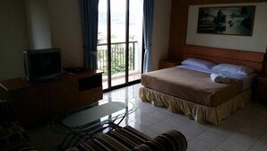 A hotel room with a bed, a TV, a desk, and a balcony with curtains. - Lumut Valley Resort Condominium (Lumut)