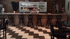 A bar area with a checkered floor, bar stools, and a shelf with bottles. - Lumut Valley Resort Condominium (Lumut)