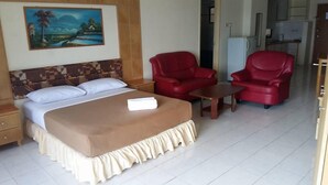 A hotel room with a bed, two red armchairs, a small table, and a painting on the wall. - Lumut Valley Resort Condominium (Lumut)