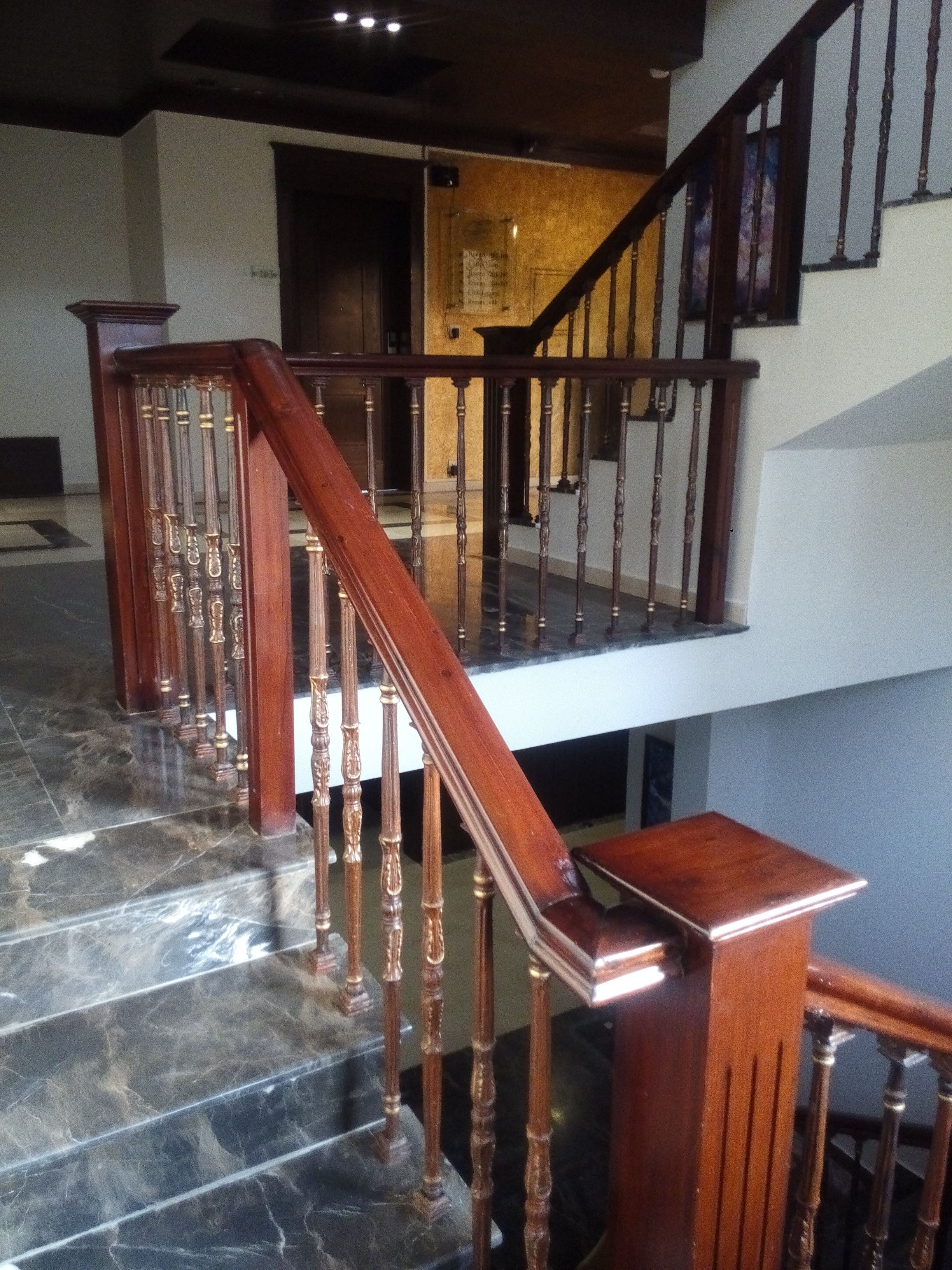 A staircase with wooden balusters and a marble floor.