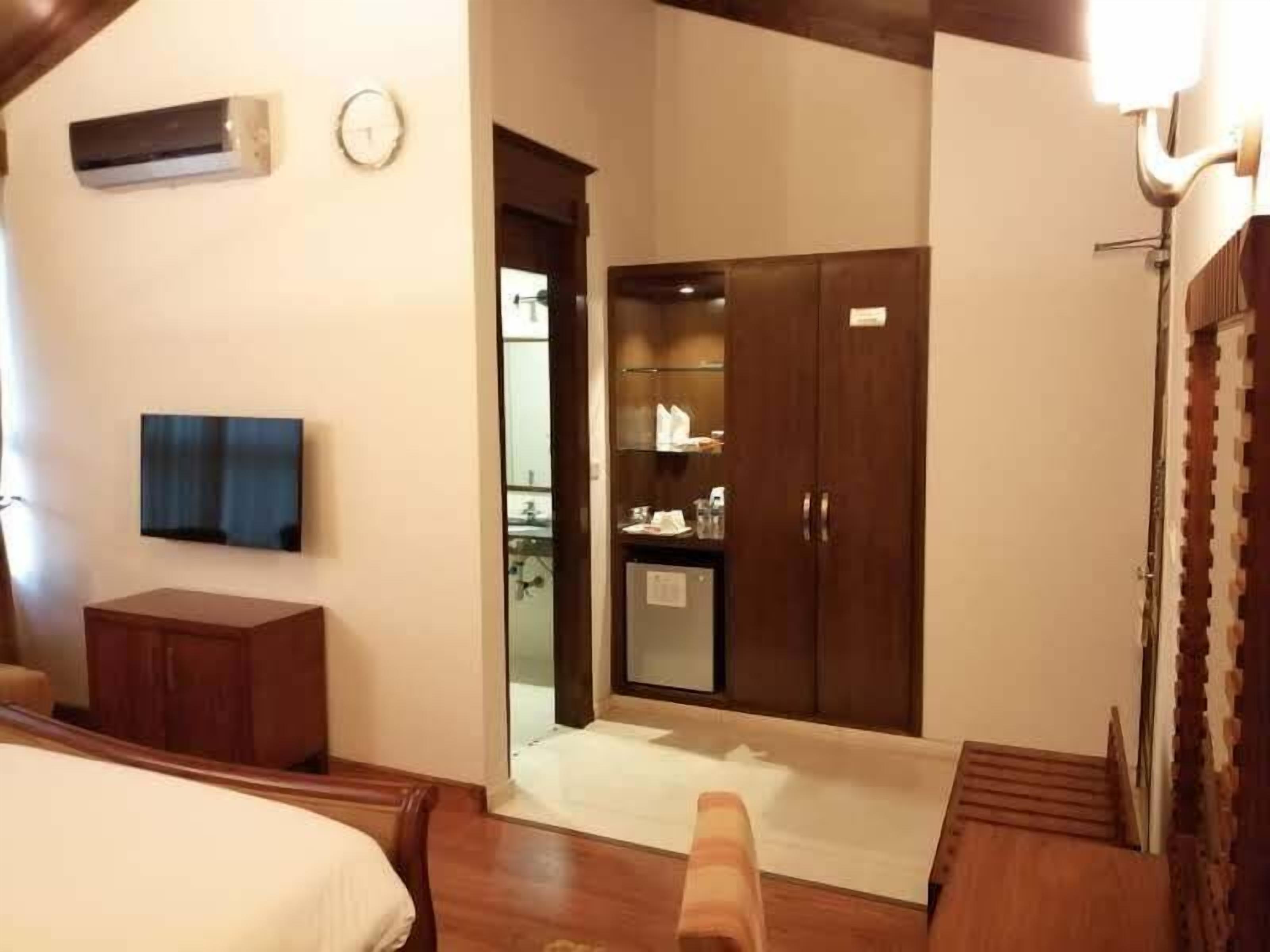 Habitación de hotel con cama, televisión, armario y un pequeño escritorio.