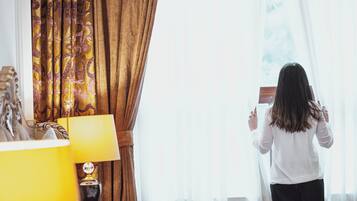 A hotel room with a bed, a nightstand with a lamp, and a window with curtains.