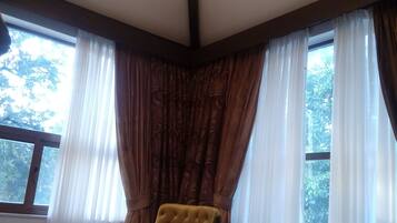 A bedroom with a large bed, a chandelier, and curtains on the windows.