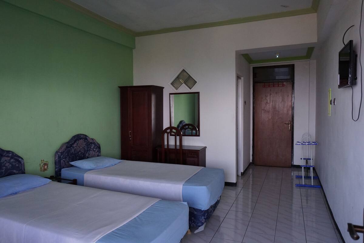 Una habitación con dos camas, un armario, un espejo y una televisión.