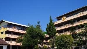 A multi-story building with balconies and a clear blue sky. - Hotel Surya Indah (Batu)