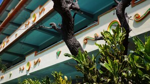 A building facade with decorative elements and a tree in the foreground. - Hotel Surya Indah (Batu)
