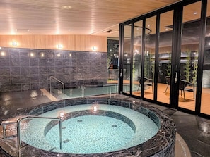 A spa area with a hot tub, a wooden ceiling, and a glass wall.