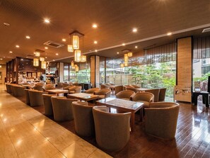 A spacious indoor area with multiple seating arrangements, including tables and chairs, and a bar area visible in the background.