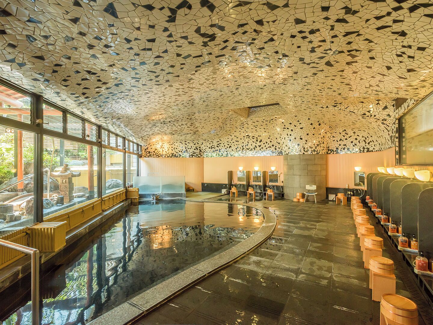 A modern spa with a mosaic ceiling, a central hot tub, and a row of sinks with mirrors.