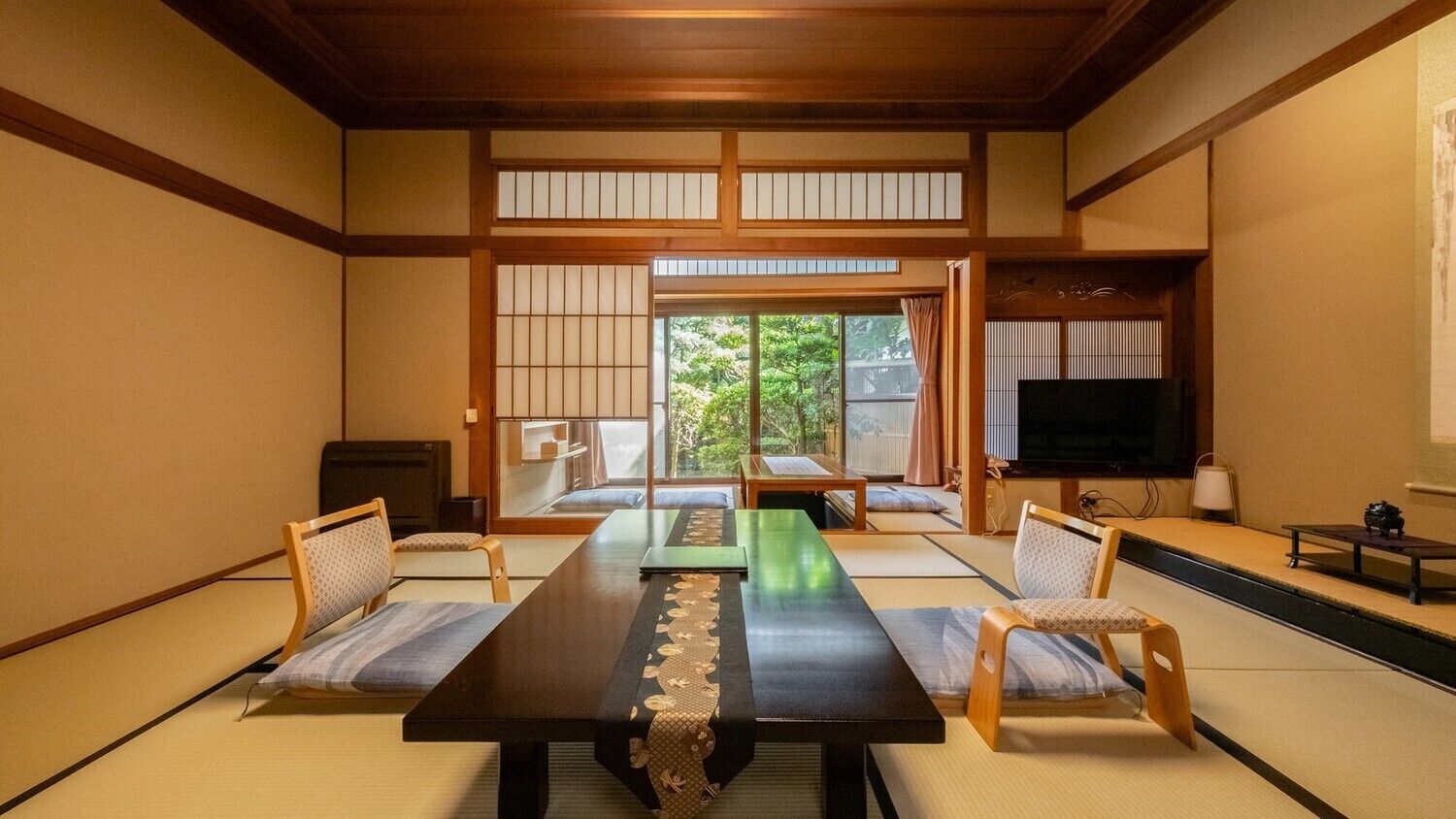 Una habitación tradicional japonesa con suelo de tatami, una mesa baja y puertas correderas.