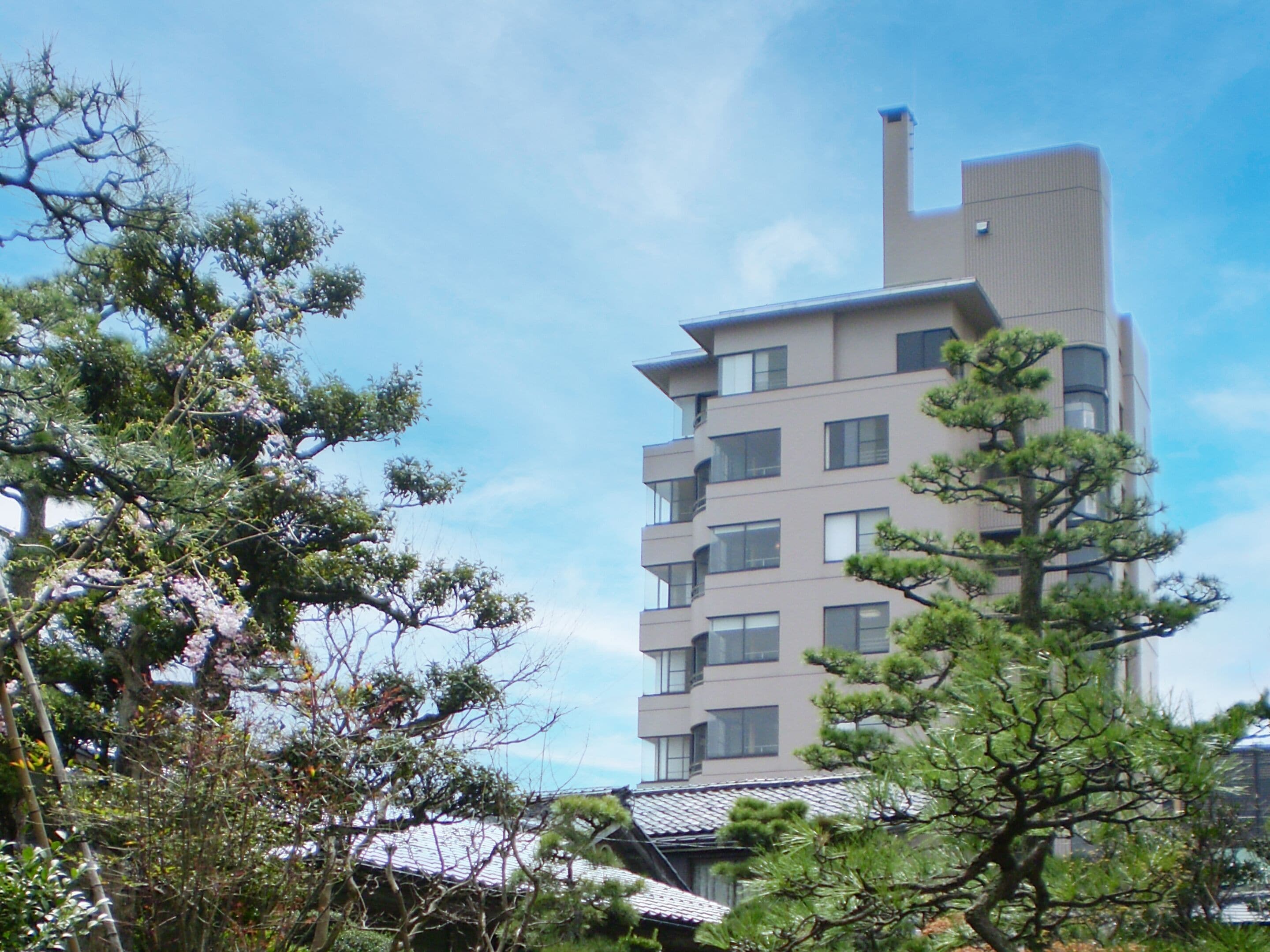 A modern multi-story building with a flat roof and a chimney.