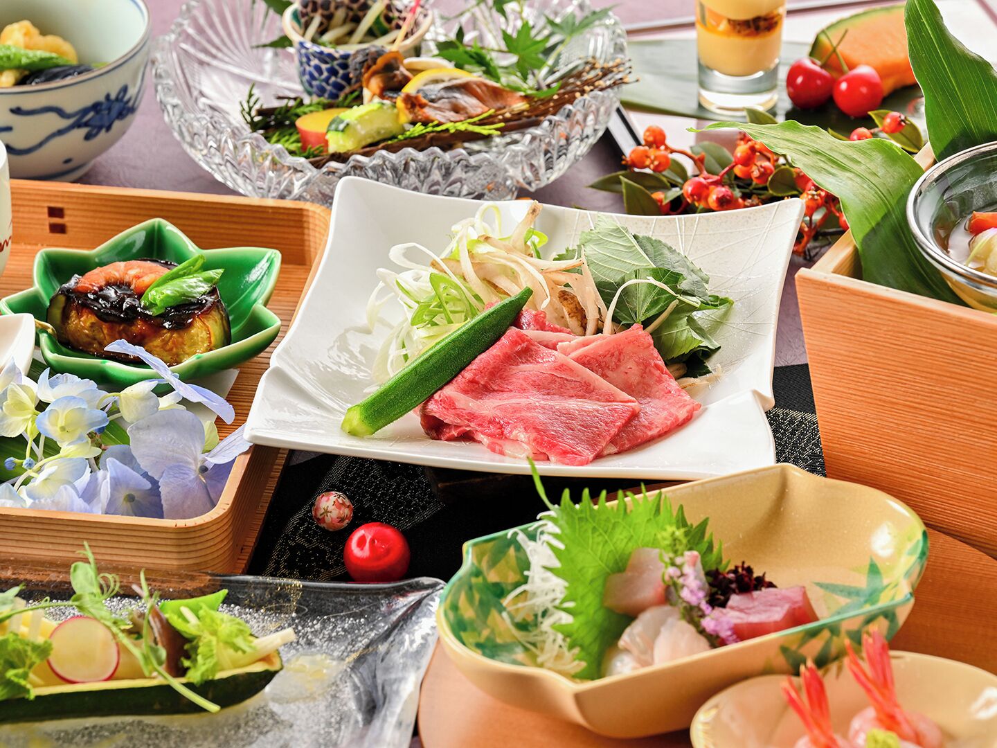 A variety of dishes on a table, including sashimi, vegetables, and a bowl of soup.