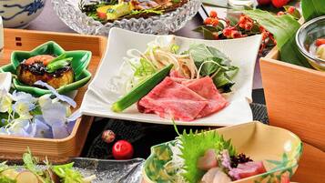 A variety of dishes on a table, including sashimi, vegetables, and a bowl of soup.