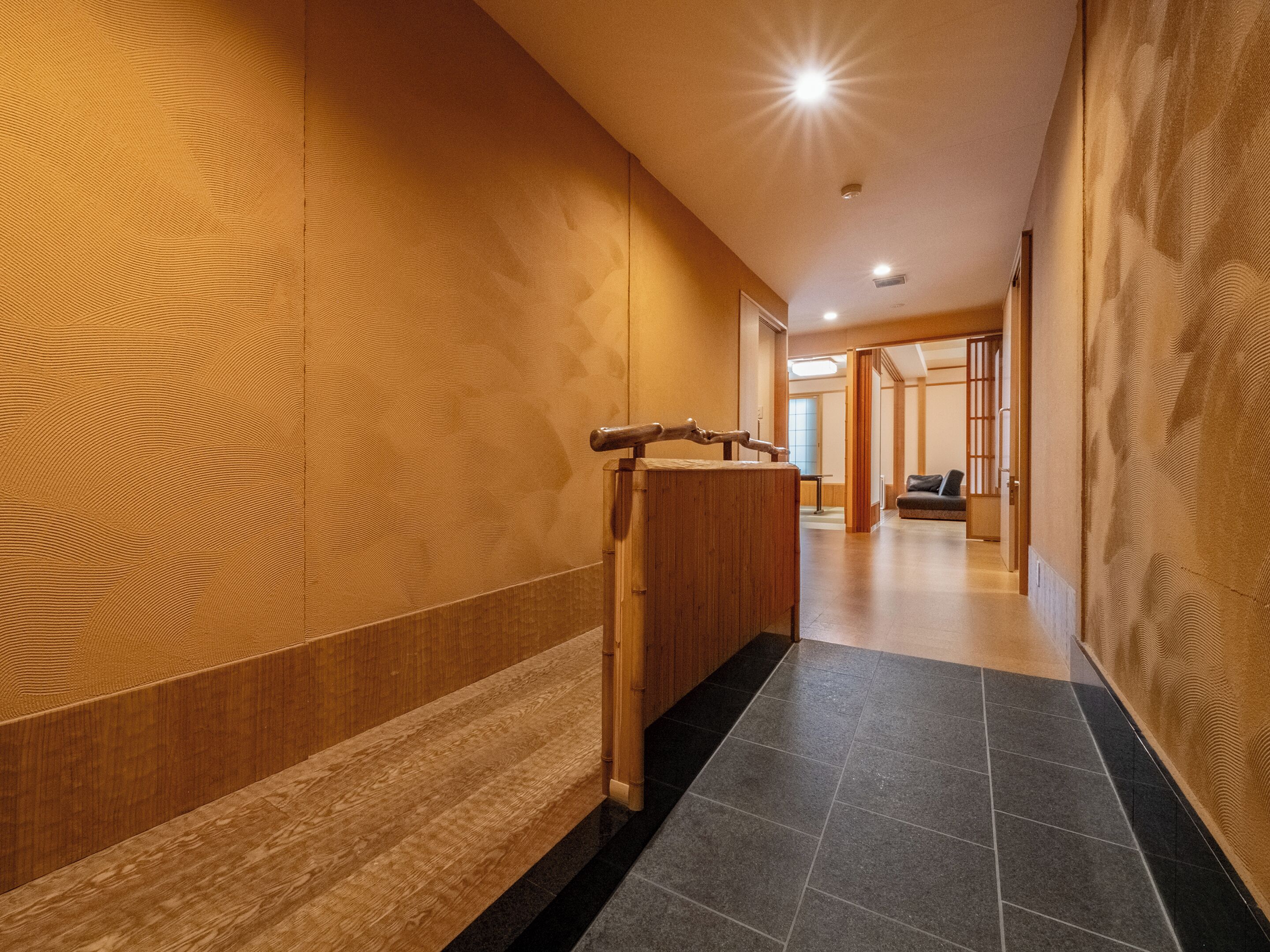 A hallway with wooden paneling, a wooden bench, and a tiled floor.