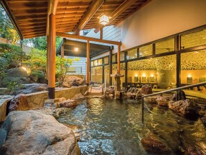 A traditional Japanese-style indoor garden with a koi pond, stone lanterns, and a wooden walkway. - Haiya (Awara)