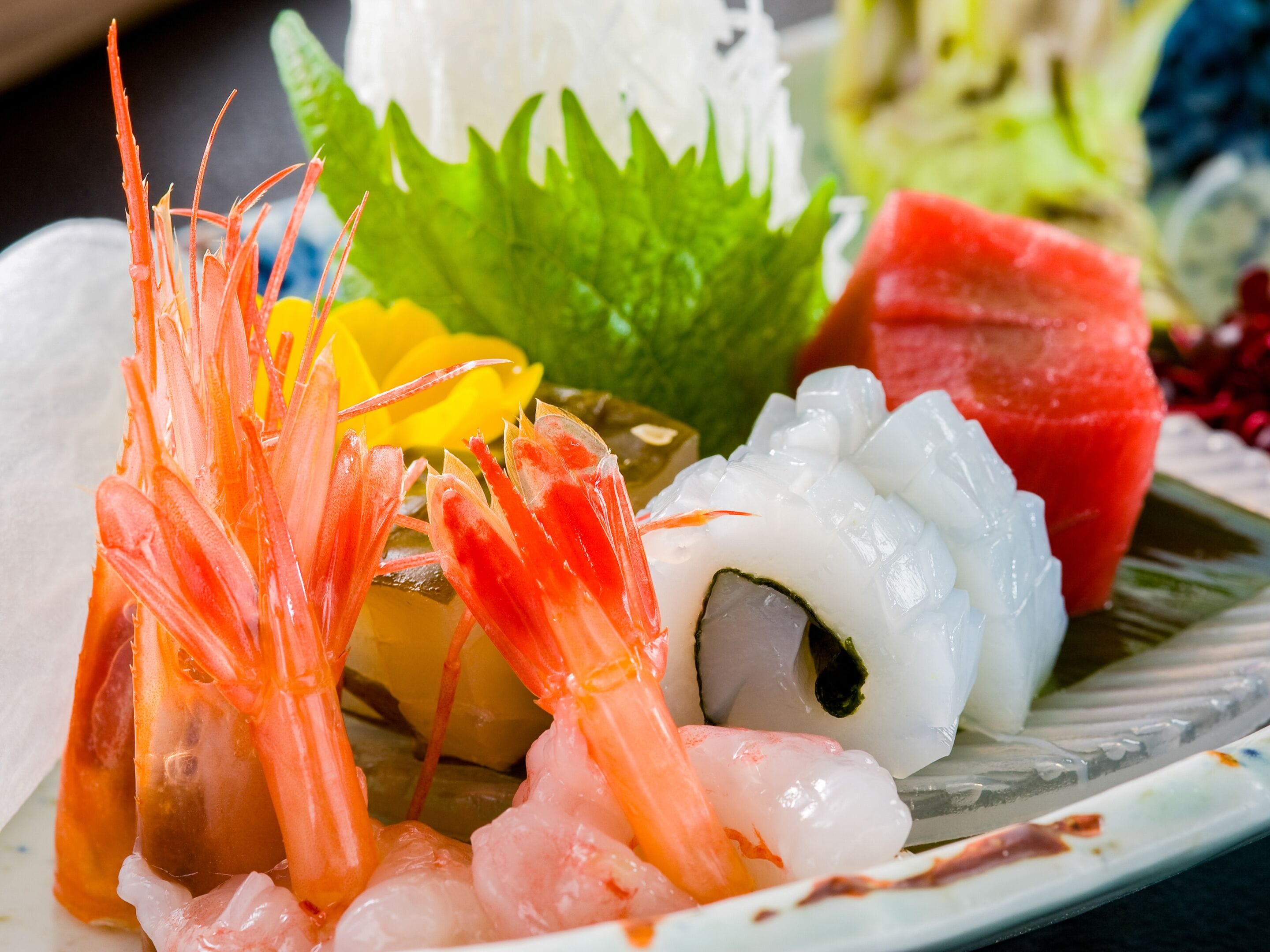 A plate of sushi with shrimp, rice, and vegetables.