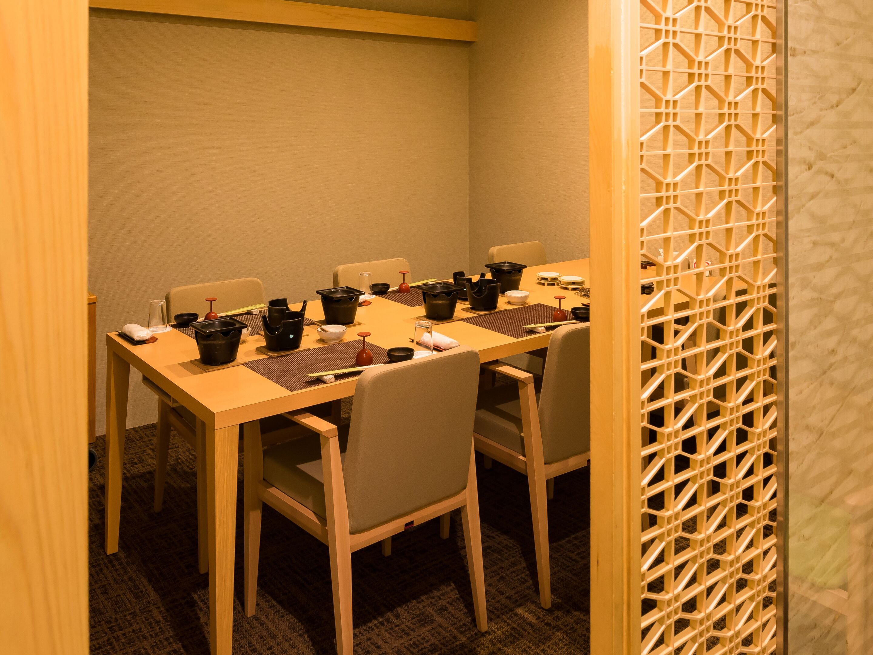 A dining area with a wooden table set for a meal, surrounded by chairs.