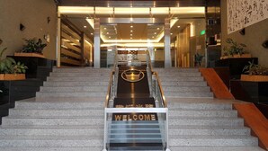 Een hotelentree met een “WELCOME”-bord onderaan de trap.