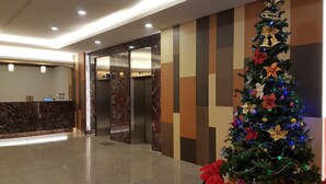 Een hal met een receptiebalie, liften en een kerstboom met kerststerren.