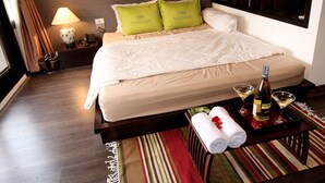 A hotel room with a neatly made bed, a bedside table with a lamp, two pillows, a bottle of wine, and two glasses on a tray. - Tomodachi House (Hanoi)