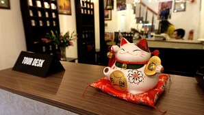 A cat-shaped decorative item on a counter with a 'Tour Desk' sign. - Tomodachi House (Hanoi)