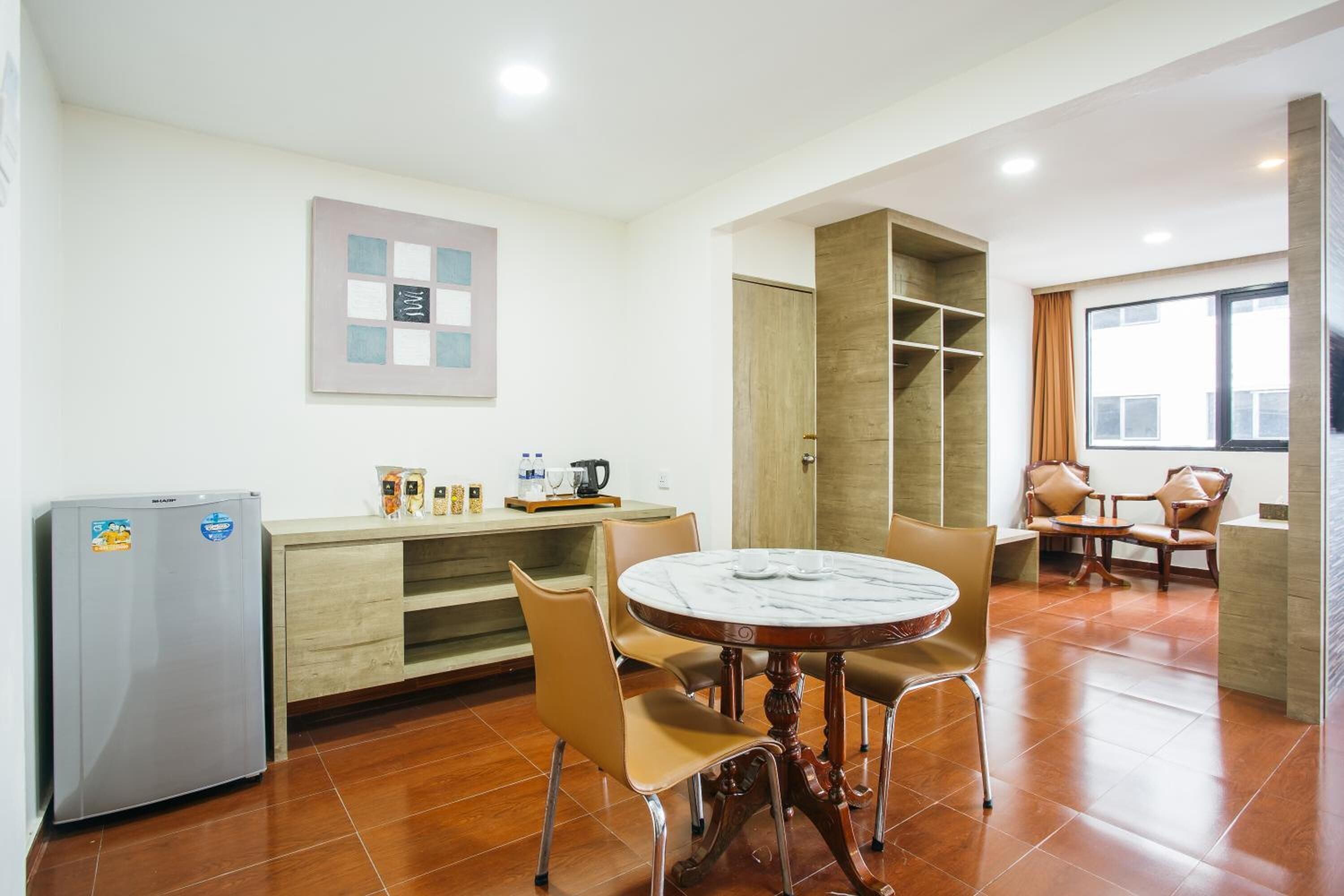 A compact kitchen with a refrigerator, a wooden cabinet, and a dining table with chairs.