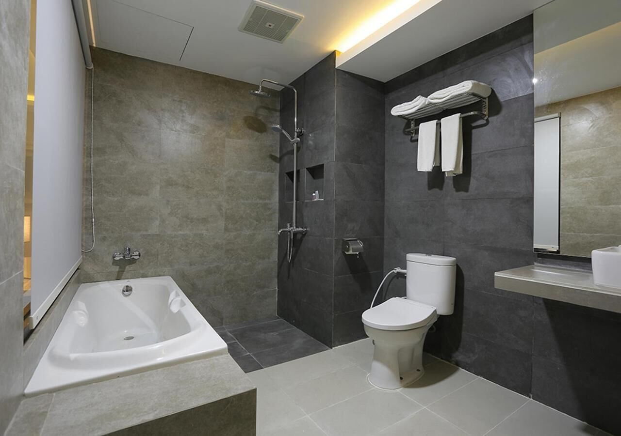 A modern bathroom with a bathtub, toilet, and a shower.