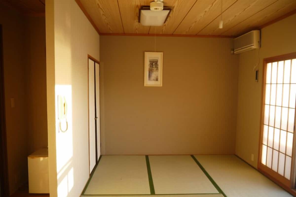 A traditional Japanese room with tatami flooring, a shoji screen, and a ceiling fan.