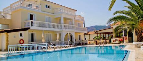 Alberca al aire libre, sombrillas en la alberca y camastros