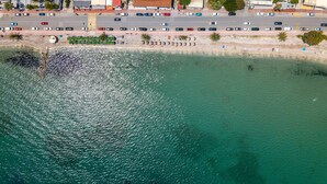 An aerial view of a coastal area with a beach, buildings, and a road. - Hotel Corfu Secret (Corfu)