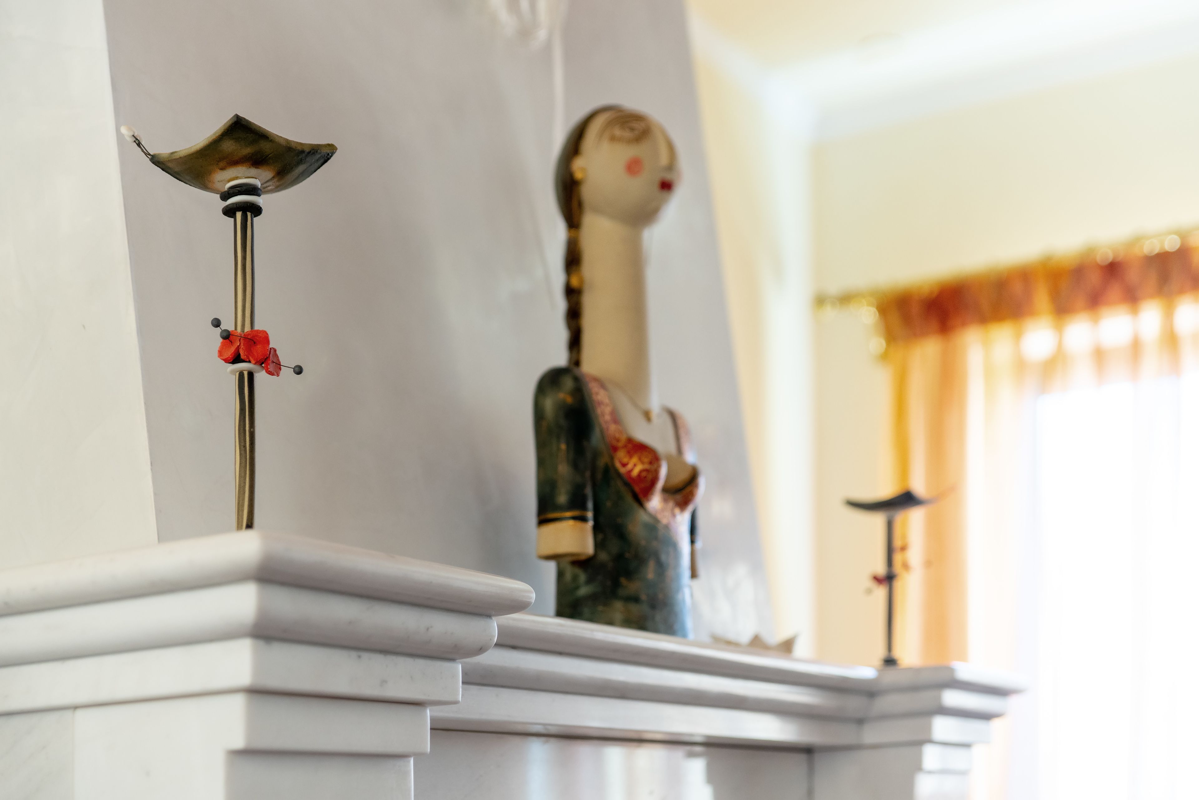A white marble fireplace with a decorative metal piece and a statue.