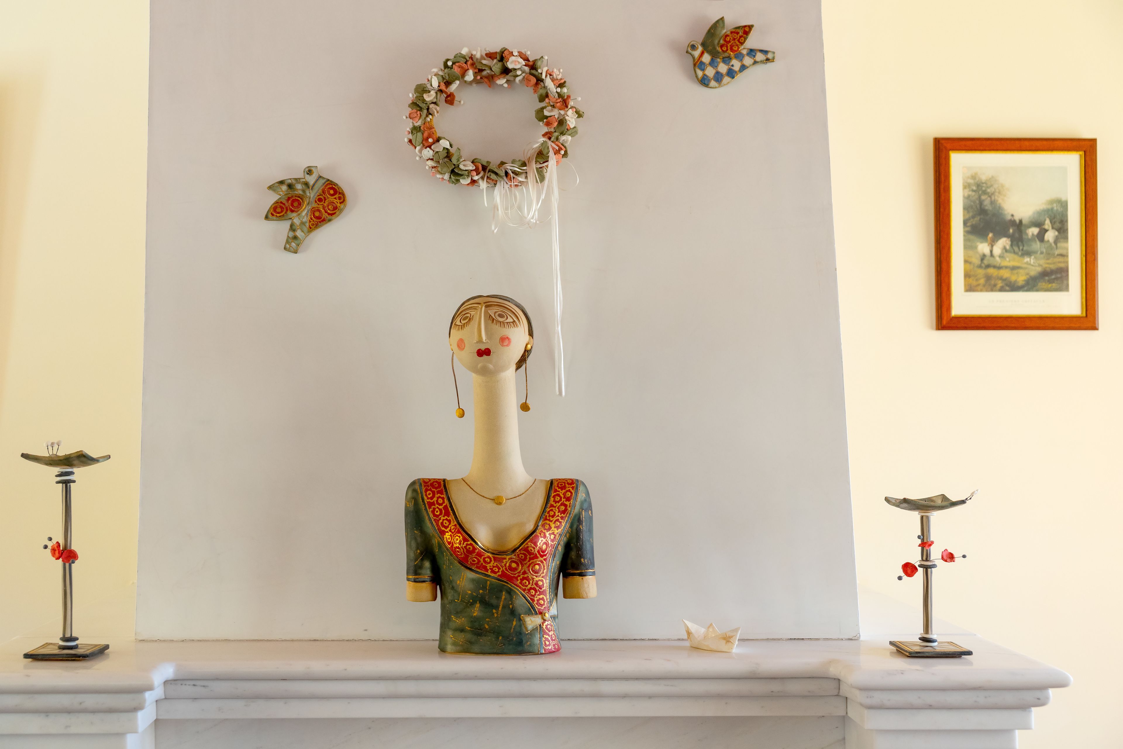 A mannequin with a floral wreath and a bird decoration on the wall.