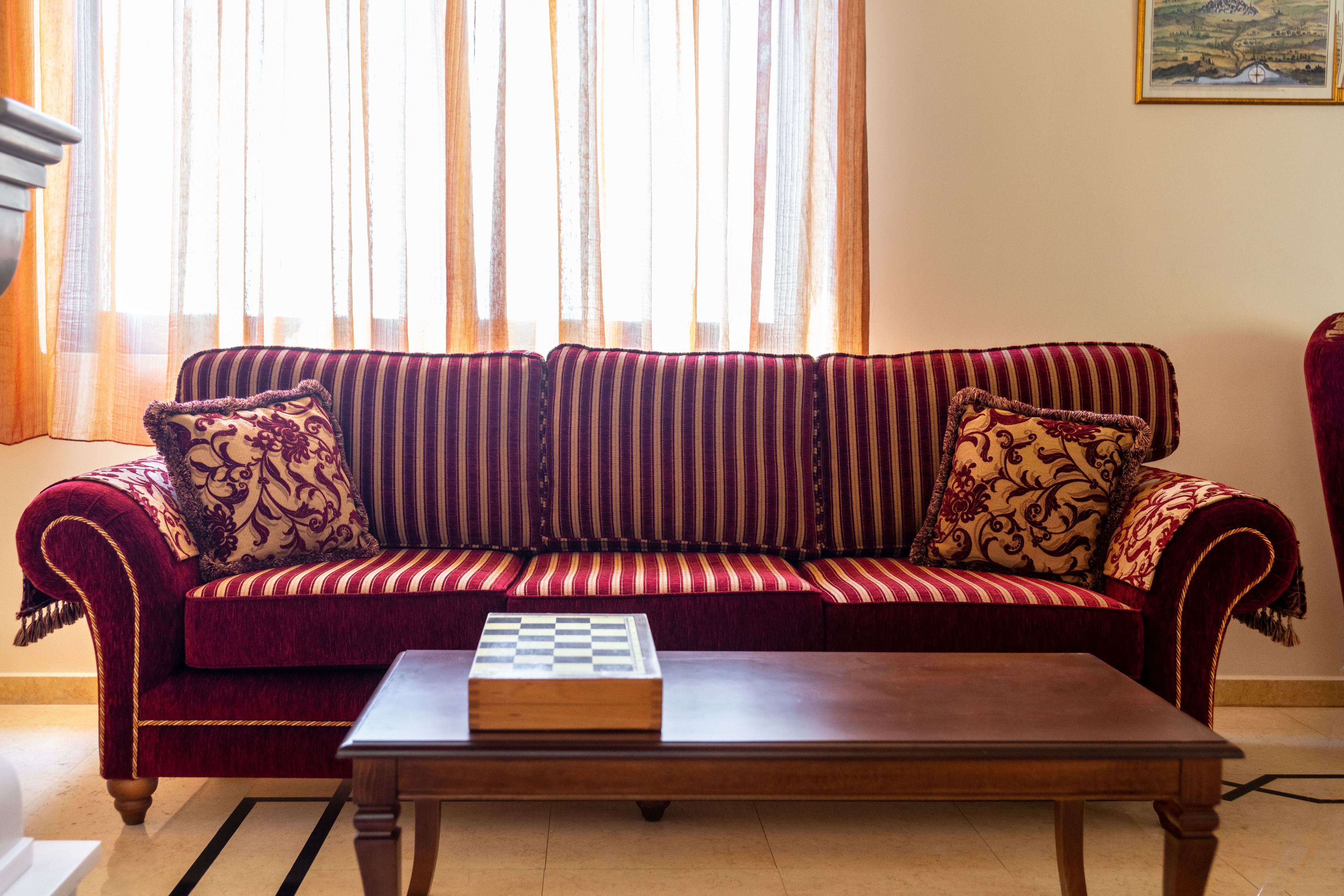 A living room with a red sofa, patterned cushions, and a wooden coffee table.