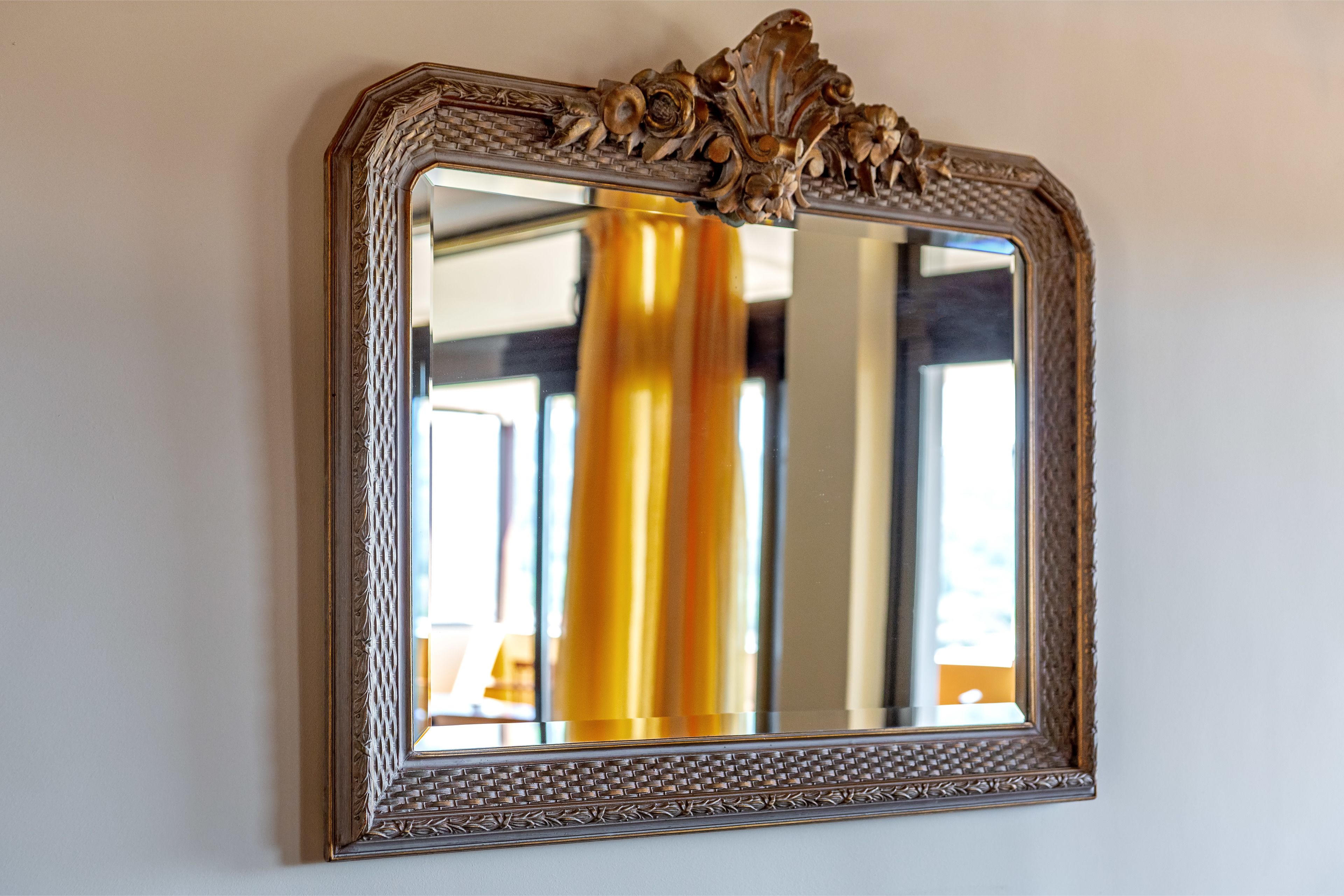 A mirror with an ornate frame mounted on a wall.