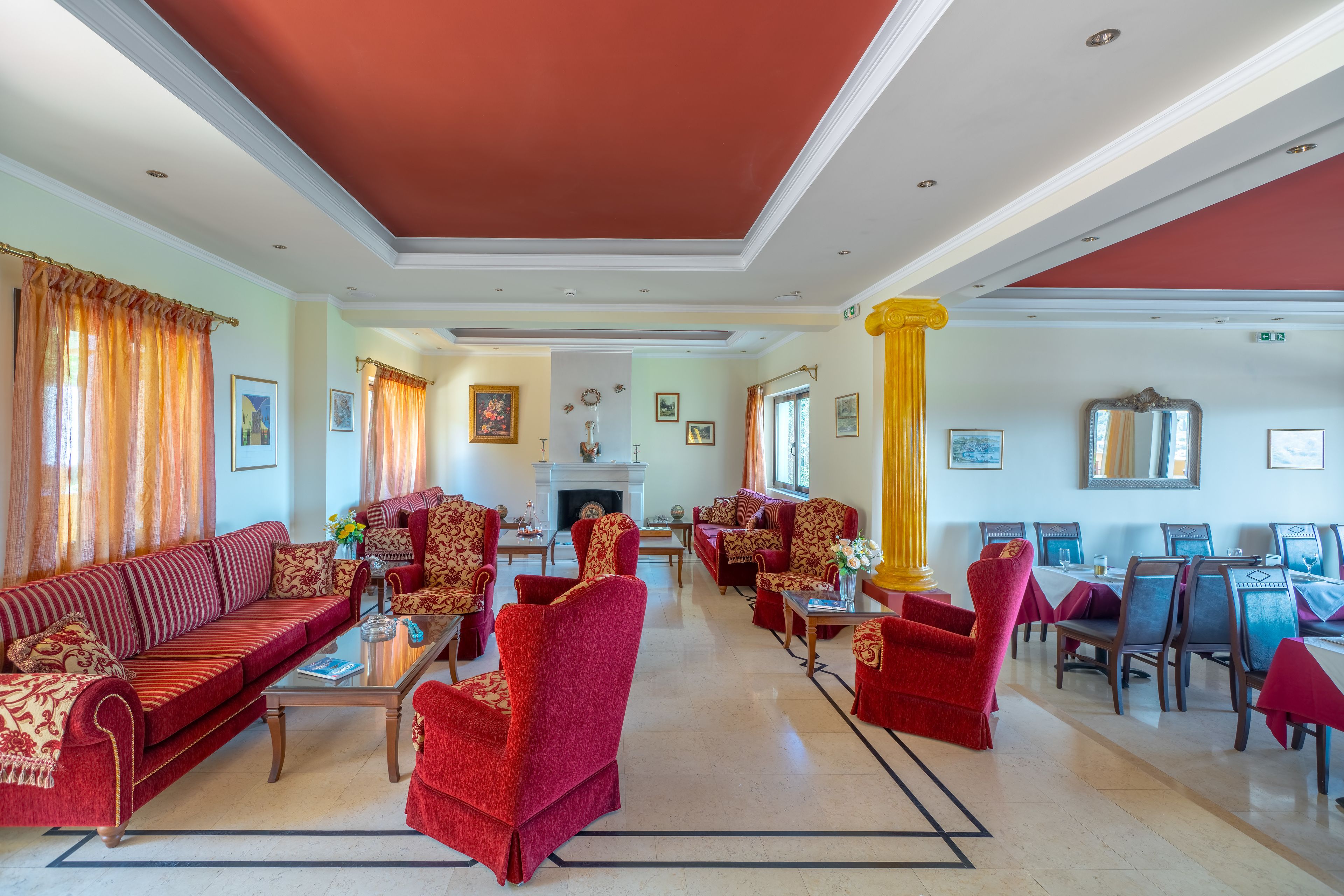 A spacious living room with a red sofa, red armchairs, and a fireplace.