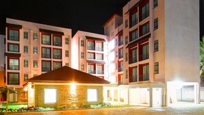 A multi-story hotel with a stone facade, balconies, and a well-lit entrance.