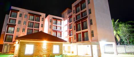 A multi-story hotel with a stone facade, multiple balconies, and a well-lit entrance area.
