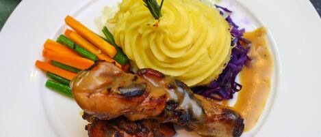 A plate with mashed potatoes, roasted chicken, carrots, green beans, and red cabbage.