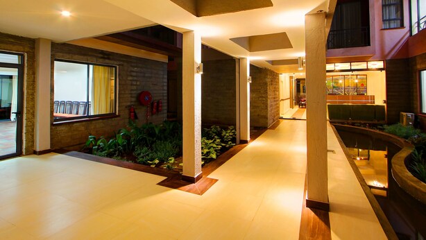 A spacious indoor area with a high ceiling, a brick wall, and a seating area with cushions.