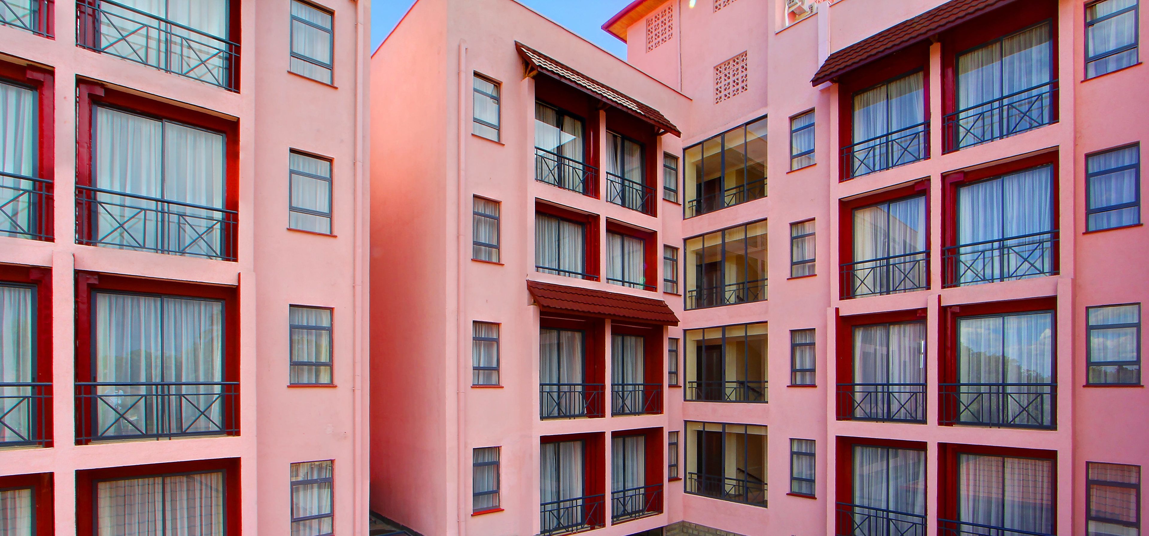 A multi-story pink building with balconies and large windows.