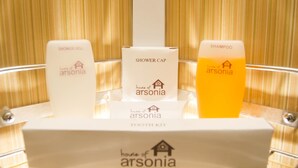 Eine Präsentation von Arsonia-Badezimmerprodukten, darunter eine Duschhaube, ein Kamm und Shampoo.