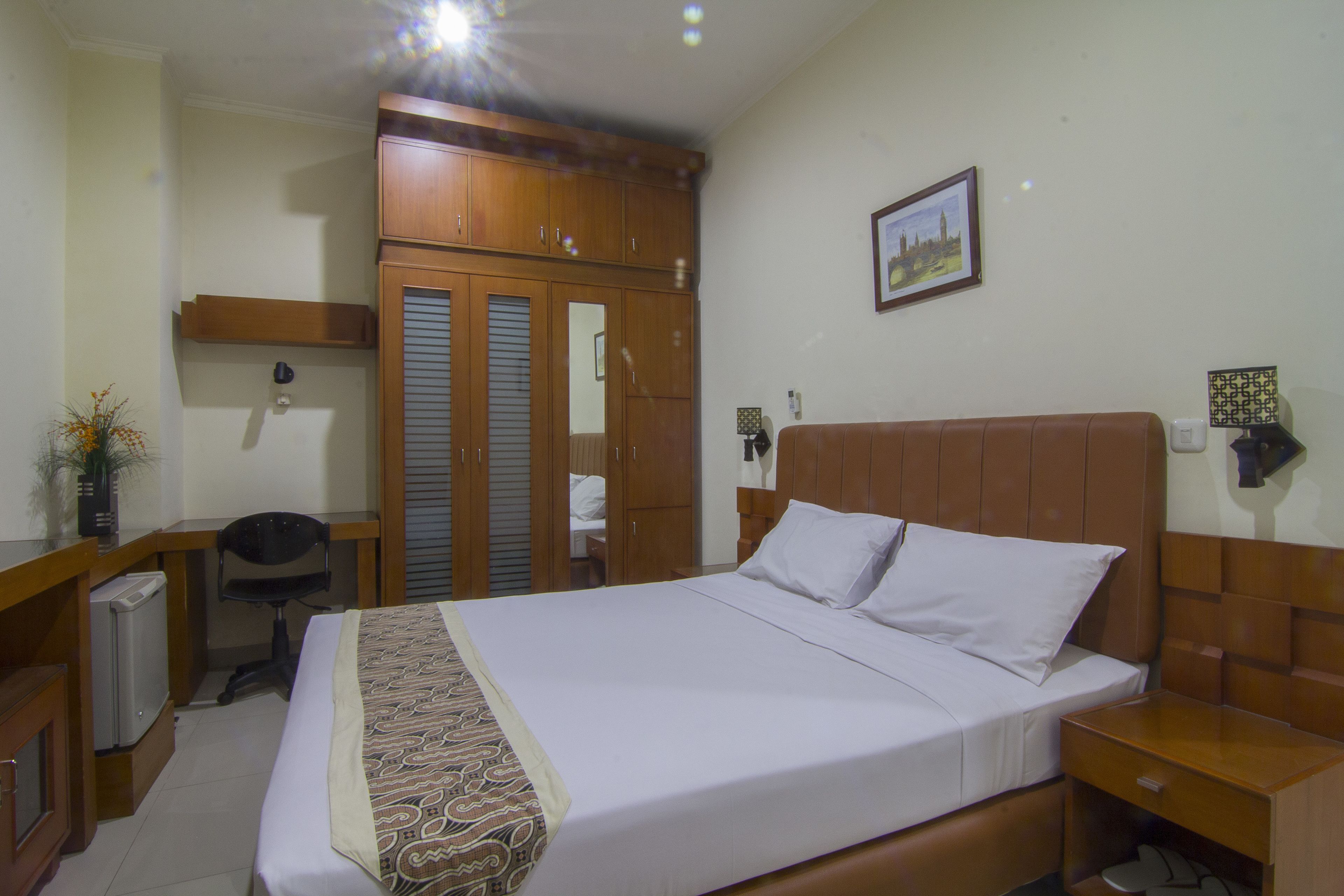 Un dormitorio ordenado con cama, mesita de noche, escritorio, silla y armario.