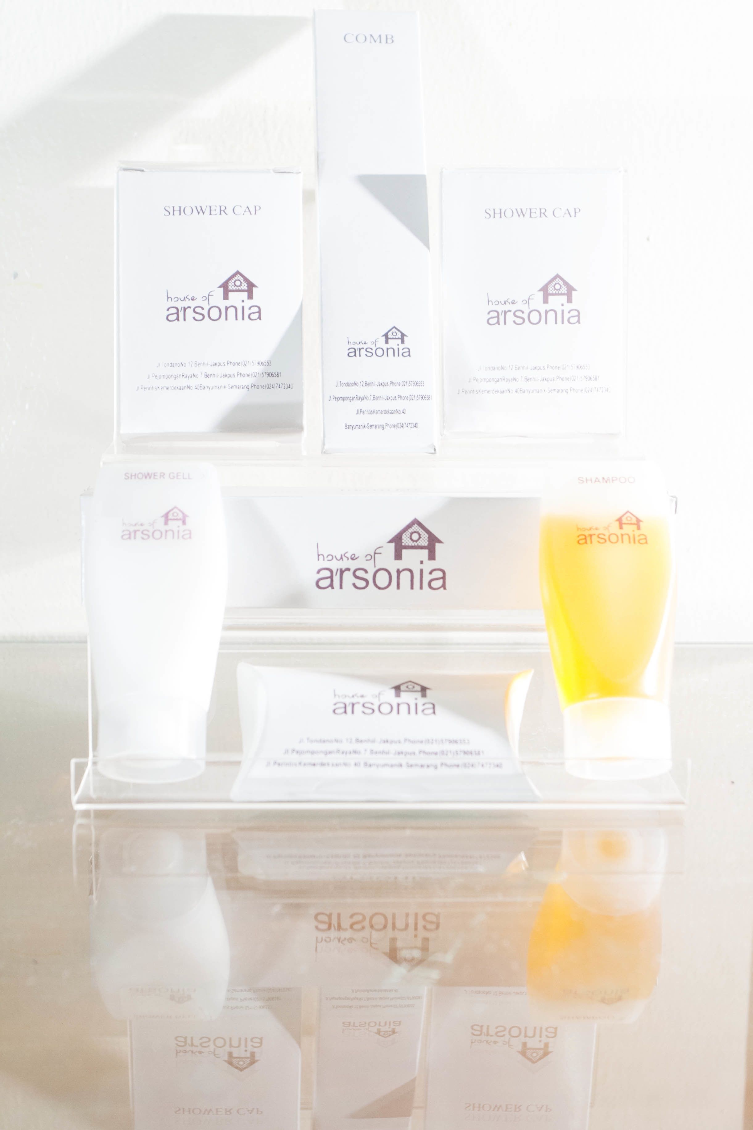 Una presentación de gorros de ducha Arsonia y una botella de champú.