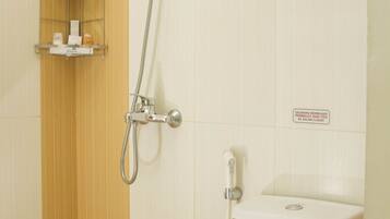 Un baño con ducha, inodoro y un estante con artículos de aseo.