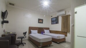 Une chambre d’hôtel avec deux lits, un bureau avec un ordinateur, une chaise et un téléviseur.
