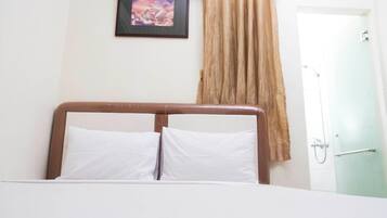 A hotel room with a bed, a framed picture on the wall, and a shower area.